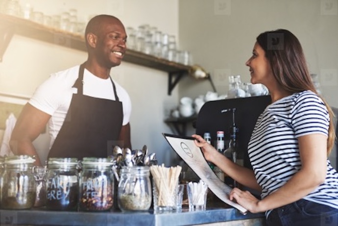 เจ้าของธุรกิจ SME กำลังพูดคุยกับลูกค้าที่หน้าร้าน สะท้อนความสัมพันธ์และความไว้วางใจระหว่างแบรนด์กับลูกค้า