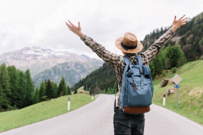 นักเดินทางสะพายเป้ท่ามกลางวิวภูเขา สื่อถึงแนวคิด Micro-Retirement และการเดินทางระยะยาว